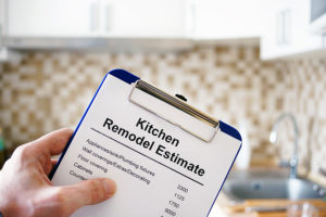 Home improvement contractor holding a blue clipboard with a kitchen remodel estimate while standing in a residential kitchen in Springfield, IL.