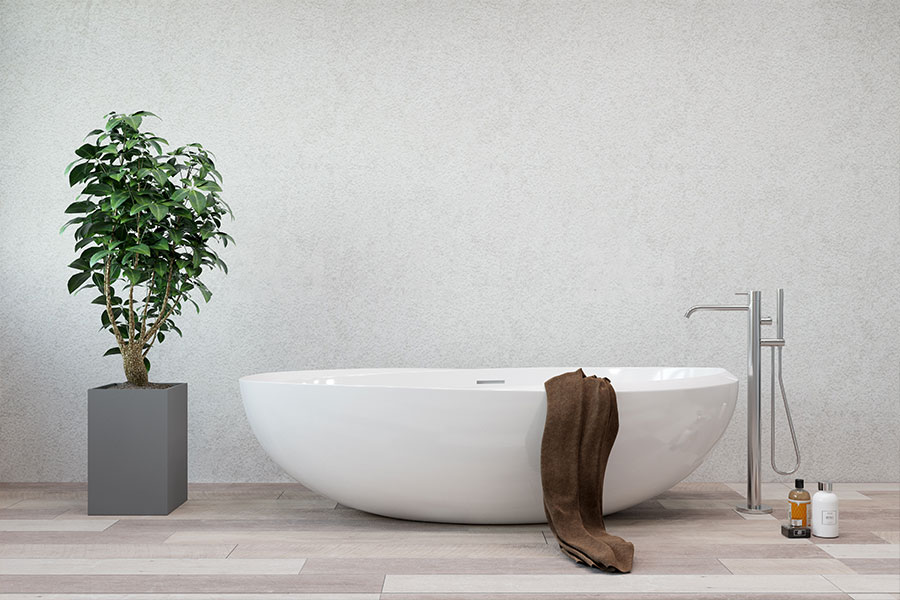 White freestanding bathtub in a residential bathroom in Springfield, IL with a decorative plant, brown towel, and white walls.