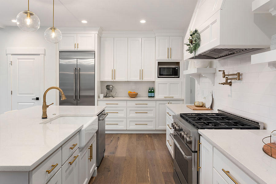 Beautiful kitchen remodel in Springfield IL with white cabinets and countertops, stainless steel appliances, and gold hardware