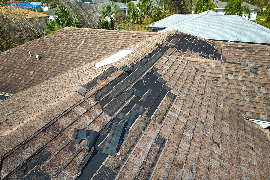 A damaged roof on a home in Springfield, IL that is missing many shingles and needs a replacement.