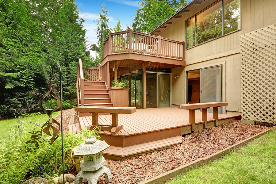 A wooden walkout deck with patio and built-in wooden benches in a backyard in Springfield, IL.