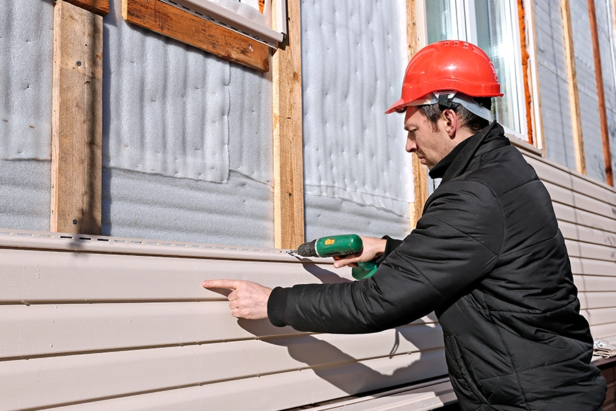 A worker professionally installs vinyl siding on the façade of this residential home in Springfield, IL.