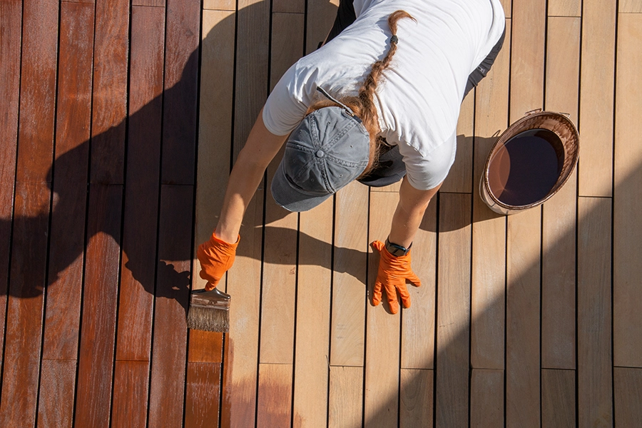 A young woman applying a deck staining color to a deck in Springfield, IL.