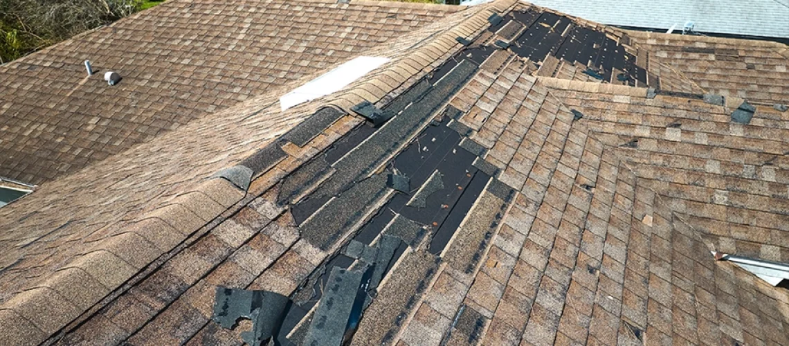 A damaged roof on a home in Springfield, IL that is missing many shingles and needs a replacement.