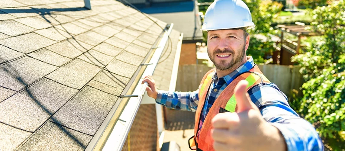 A professional technician in a safety vest and hard hat inspects a residential roof in Springfield, IL.